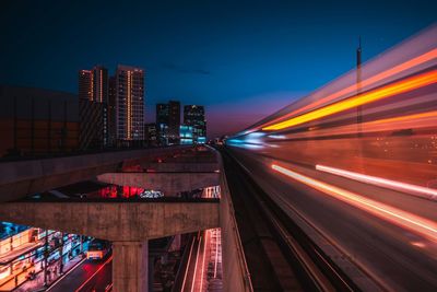 Light trails on bridge against sky at night