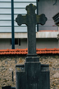 Close-up of cross on old temple against building
