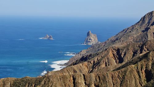 Scenic view of sea and mountains against blue sky