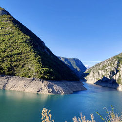 Scenic view of lake and mountains against clear blue sky