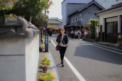 Full length of woman walking on road in city