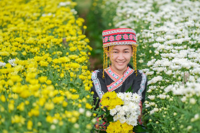 Portrait of smiling woman wearing traditional clothing standing amidst flowering plants