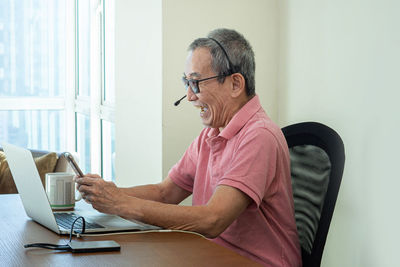 Midsection of man using mobile phone while sitting on table