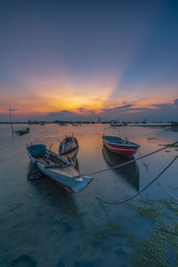 Boat moored on sea against sky during sunset