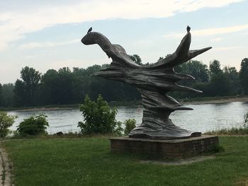 Statue by lake against sky