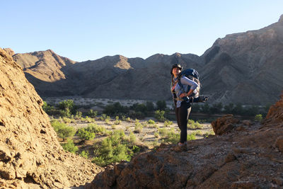 Man standing on rocky mountain against clear sky