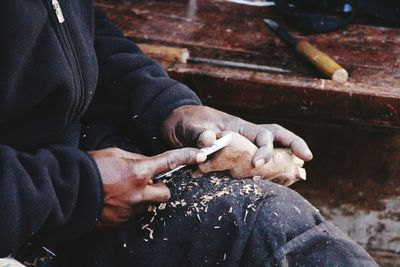 Midsection of craftsperson carving on wood at workshop