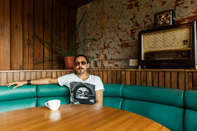 Portrait of young man sitting on sofa at table