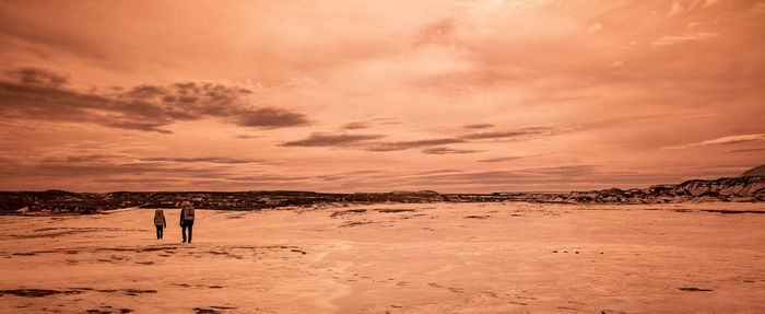 Man standing on beach against sky during sunset