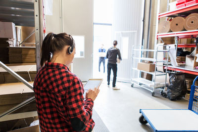 Female using digital tablet while male workers standing at doorway