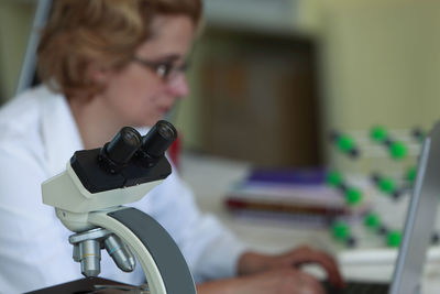 Close-up of microscope with scientist in background