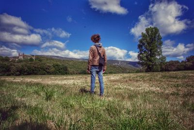 Rear view of person standing on field against sky