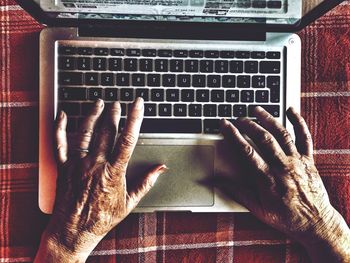 Close-up high angle view of hands using laptop keyboard