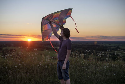 Full length of woman standing on field against sky during sunset