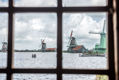 Traditional windmills by river seen through window