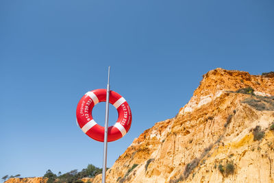Low angle view of red flag against clear blue sky
