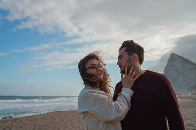 Couple enjoying at beach against sky