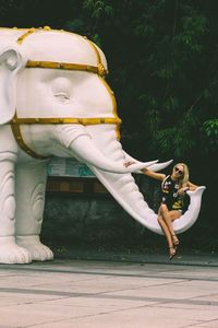 Woman sitting on elephant statue 