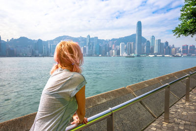 Woman looking at view while standing by railing against river