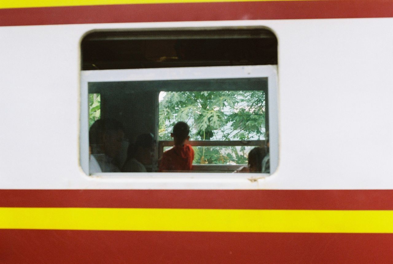 REAR VIEW OF TWO PEOPLE WAITING IN TRAIN