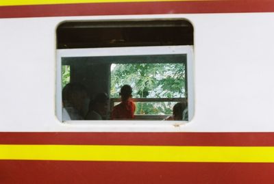 Rear view of two people seen through train window