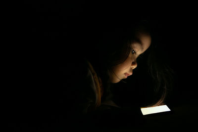 Portrait of woman looking away against black background