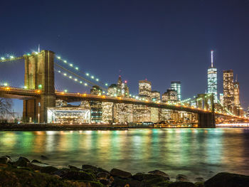 Illuminated bridge over river and buildings at night