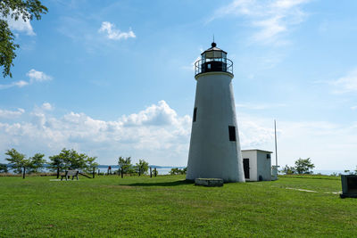 Lighthouse on field against sky