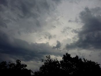 Low angle view of silhouette trees against cloudy sky