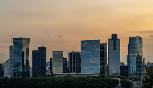 Skyscrapers in city against sky during sunset