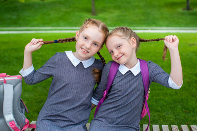 Portrait of smiling sisters sitting on seat