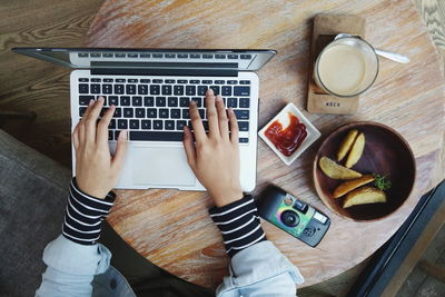 Directly above of shot man using laptop with breakfast on table