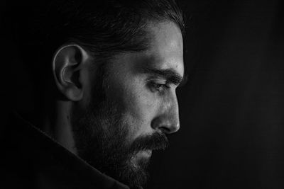 Close-up portrait of mid adult man against black background