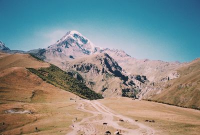 Scenic view of snowcapped mountains against clear blue sky