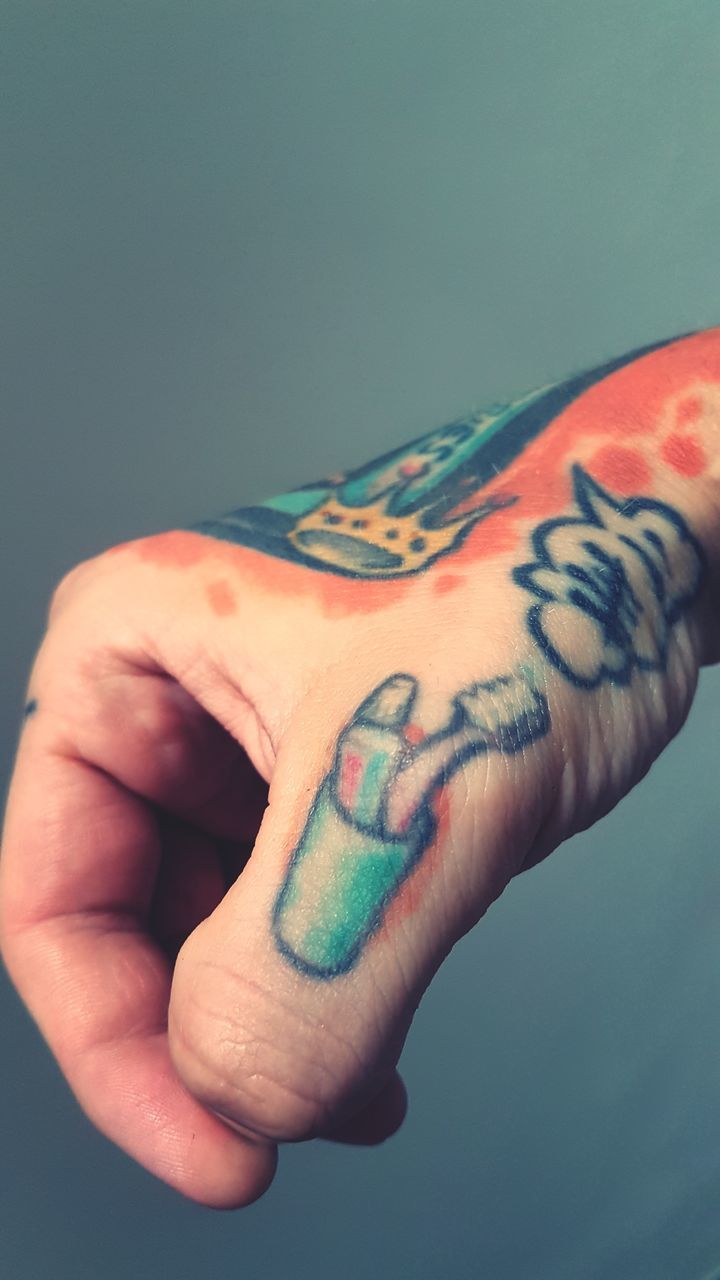 CLOSE-UP OF HAND WITH TATTOO ON BACKGROUND