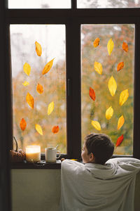 Rear view of woman looking through window