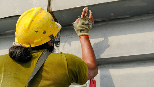 Rear view of man working with umbrella