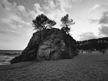 Rock formation on beach against sky