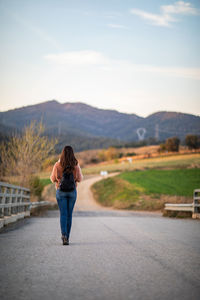 Rear view of woman walking on road against sky