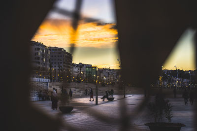Buildings seen through window against sky during sunset