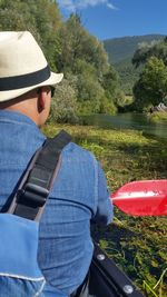 Rear view of man rowing boat in river on sunny day