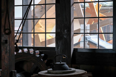 Kettle on table with water wheel seen from window at watermill