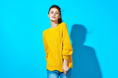 Portrait of a smiling young woman against blue background