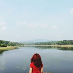 Rear view of woman looking at lake against sky