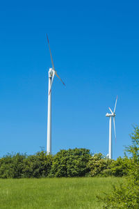 Windmill on field against clear blue sky