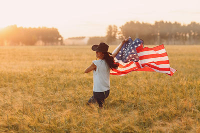 Side view of woman holding american flag on field