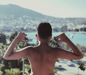 Rear view of shirtless man standing in water