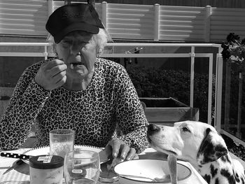 Senior woman with dog having food and drink in restaurant