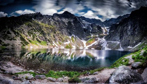 Scenic view of river and mountains against cloudy sky