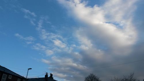 Low angle view of power lines against cloudy sky